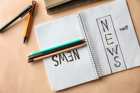 Notebook with words NEWS on color background