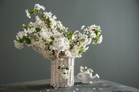 Vase with beautiful blossoming branches on table against grey backgroundの写真素材