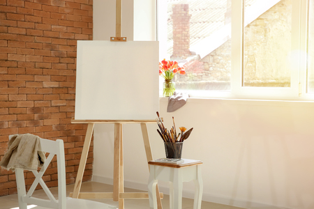 Easel with canvas and artist's supplies in workshopの写真素材