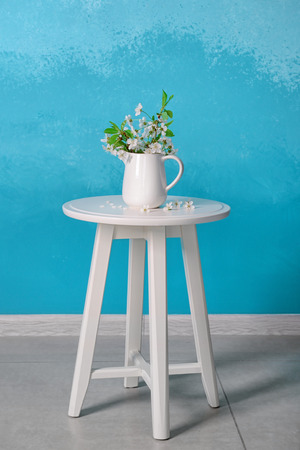Vase with beautiful blossoming branches on table against color wallの写真素材