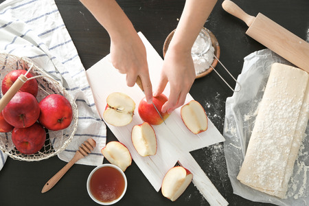 Woman cutting apples for pastry on wooden boardの写真素材