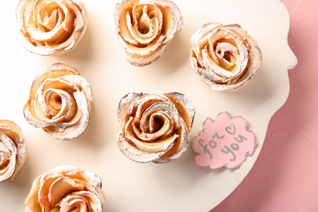 Board with tasty apple roses from puff pastry on tableの写真素材