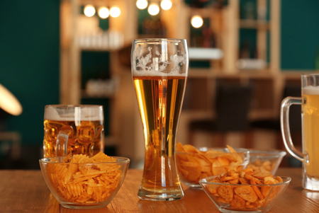 Glasses with beer and snacks on table in barの写真素材