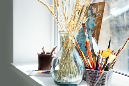 Vase with spikelets and paint tools on windowsill in artist's workshopの写真素材