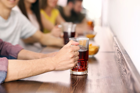 Young man with friends drinking beer in barの写真素材