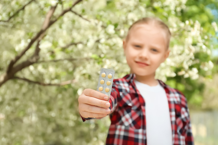 Little girl with pills near blooming tree. Allergy conceptの写真素材