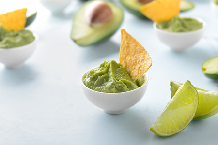 Bowl with delicious guacamole and nachos on light backgroundの写真素材