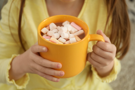 Cute little girl with cup of hot cocoa drink at home, closeupの写真素材