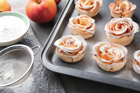 Baking tray with tasty rose shaped apple pastry on tableの写真素材
