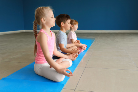 Little children practicing yoga indoorsの写真素材