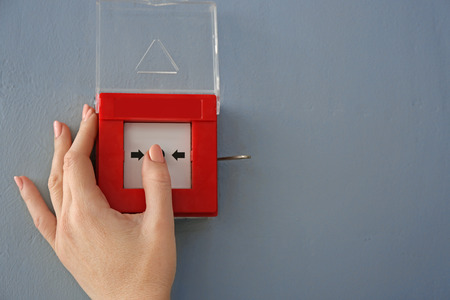 Young woman using fire alarm system indoors
