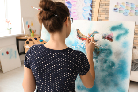 Female artist painting picture in workshopの写真素材