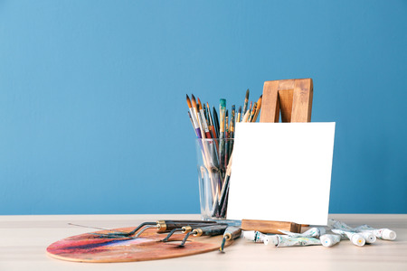 Set of painting tools with canvas on table against color backgroundの写真素材