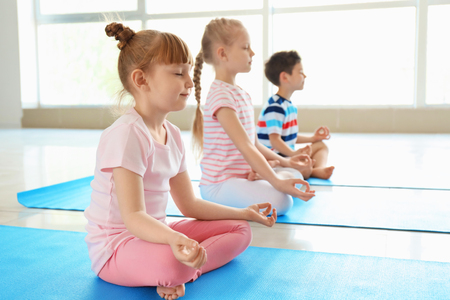 Little children practicing yoga indoorsの写真素材