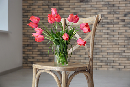 Vase with beautiful tulips on wooden chair indoorsの写真素材