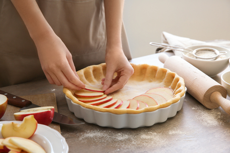Woman preparing apple pie at tableの写真素材