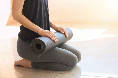 Young woman with yoga mat indoorsの写真素材