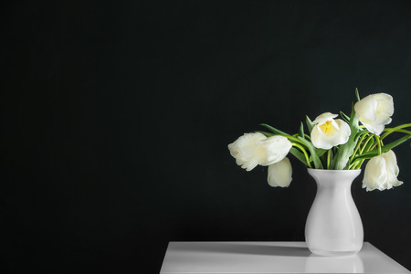 Vase with beautiful tulips on table against dark backgroundの写真素材