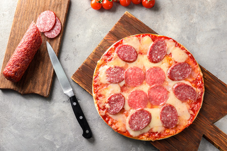 Wooden board with tasty pepperoni pizza on tableの写真素材