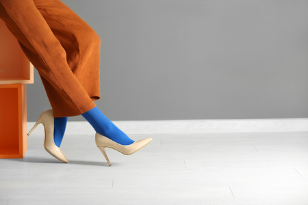 Legs of beautiful young woman in tights and trousers against color wallの写真素材