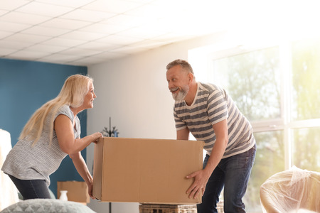 Mature couple with moving box at new homeの写真素材