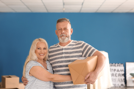 Mature couple with moving box at new homeの写真素材