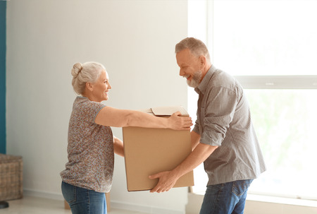 Mature couple with moving box at new homeの写真素材