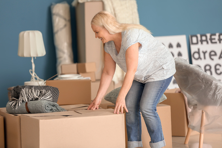 Mature woman with moving boxes and belongings at new homeの写真素材