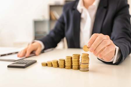 Woman stacking coins on table. Savings conceptの写真素材