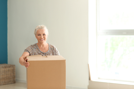 Mature woman with moving box at new homeの写真素材