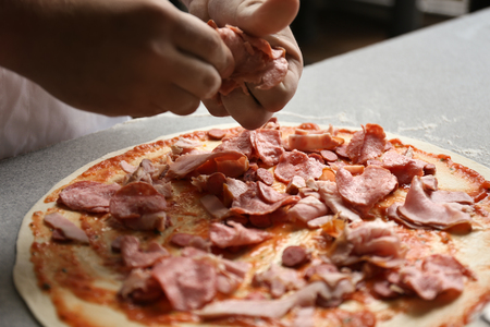 Chef preparing pizza on table in restaurant kitchenの写真素材