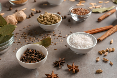 Bowls with various spices on grey  background