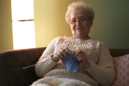 Senior woman knitting warm sock at homeの写真素材