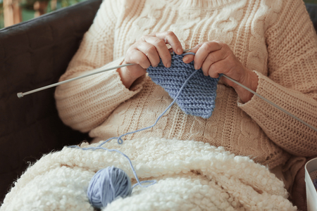Senior woman knitting warm sock at homeの写真素材
