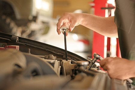 Young mechanic checking engine oil level in car service centerの写真素材