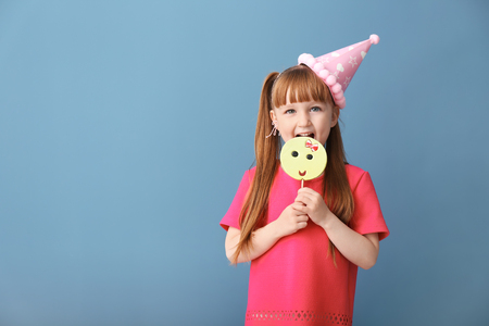 Cute little girl with lollipop on color backgroundの写真素材