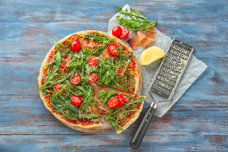Wooden board with tasty pizza on tableの写真素材