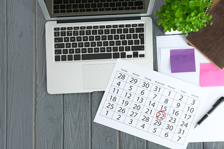 Calendar with notes and laptop on wooden backgroundの写真素材