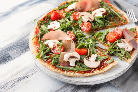 Wooden board with tasty pizza on tableの写真素材