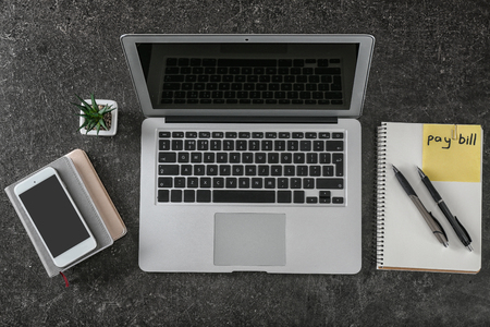 Sticker with phrase PAY BILL, laptop and phone on grey backgroundの写真素材