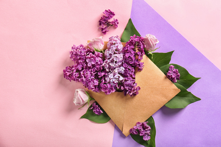 Open mail envelope with lilac flowers and roses on color backgroundの写真素材