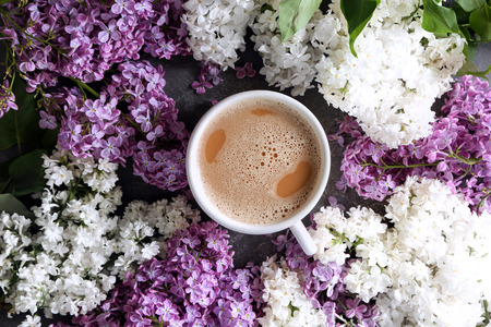 Beautiful blossoming lilac with cup of coffee on table, top viewの写真素材