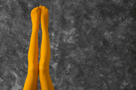 Legs of beautiful young woman in color tights on dark textured backgroundの写真素材