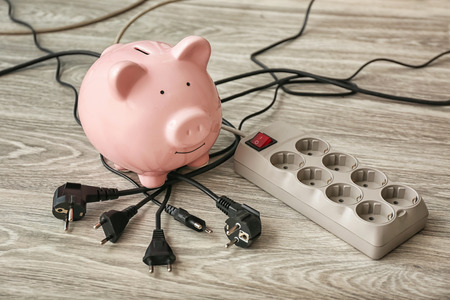 Piggy bank, plugs and power strip on floor. Electricity saving conceptの写真素材