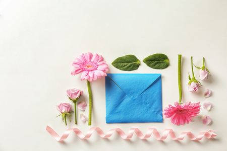 Flat lay composition with flowers and envelope on white backgroundの写真素材