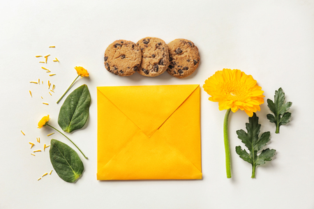 Flat lay composition with flowers, cookies and envelope on white backgroundの写真素材