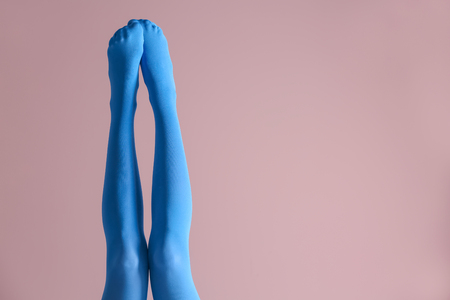Legs of beautiful young woman in bright tights on color backgroundの写真素材