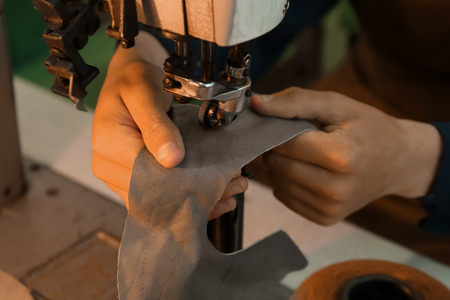 Man using sewing machine in leather workshop, closeup