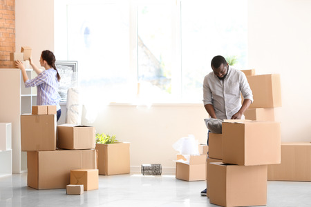 Interracial couple unpacking boxes indoors. Moving into new house