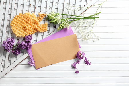 Mail envelopes with flowers and waffles on white wooden backgroundの写真素材